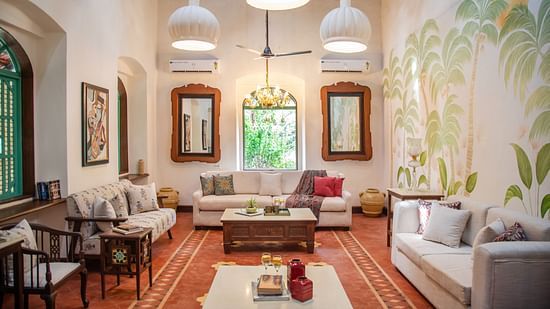 An image of a living area with sofas and centre tables, photo frames on the wall, tables on each corners where decorative items are placed at Lamrin Ucassaim Hotel, Goa