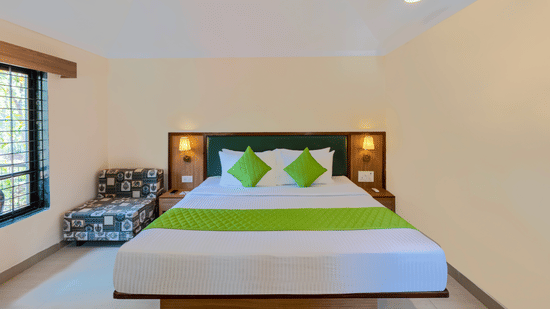 Front view of a classic room bed with green accents, bedside lamps, and minimal decor.