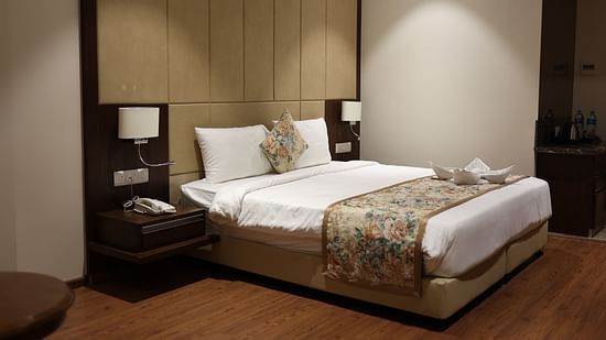 Standard Room at Pride Hotel Bhopal featuring a double bed with two nightstands attached to the large headboard and lamps on both sides