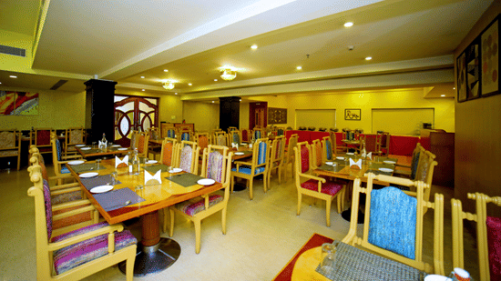 Indoor dining area with wooden tables and chairs at Raj Park Hotel, Tirupati.