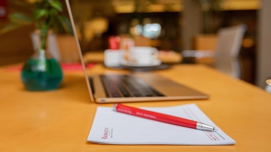A workspace with a laptop, notepad, and a flower vase at Ramada by Wyndham Addis, Addis Ababa.