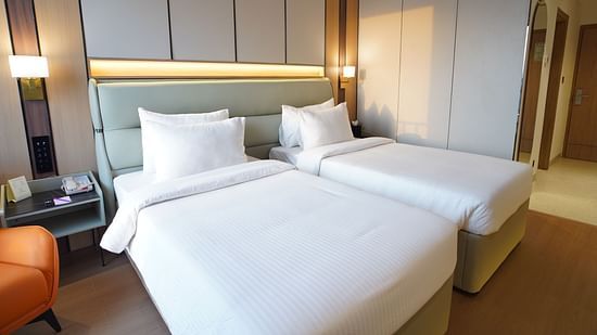 A comfortable hotel club room displays a king-sized bed with white bedding, a bedside table with a lamp, and a partial view of the rooms decor -  The Orchid Hotel, Chandigarh
