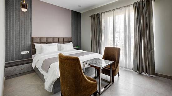 Grey themed Deluxe room with king size bed and brown chairs - The White Moon