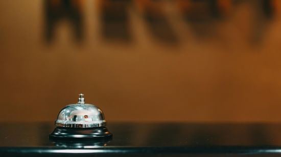 A hand bell places on a counter, with blurred image of writing on a wall.