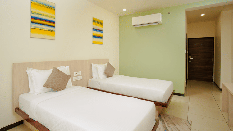 Hotel room interior with three beds and an air conditioning unit at Arawali Ananta Elite, Jaipur.