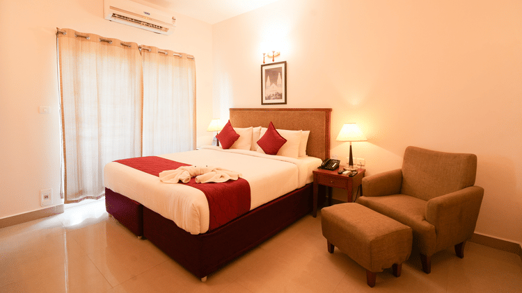 Grandeur Room featuring a plush bed and a couch with ottoman next to the nighstand