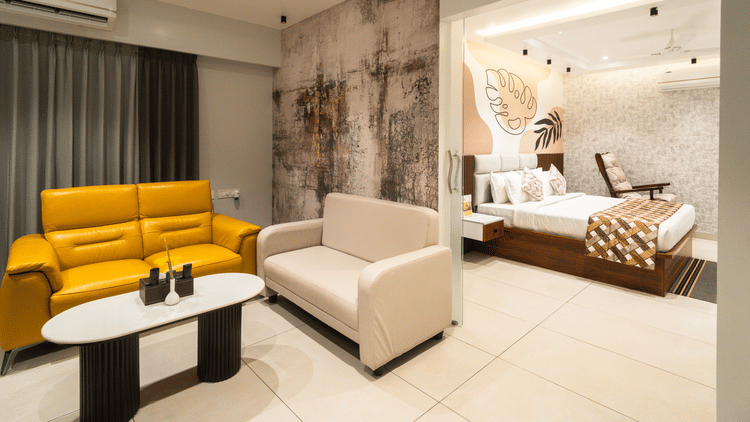 An image of a room with a plush bed in the bedroom and sofas placed around a coffee table in the living room - MGM Whispering Meadows