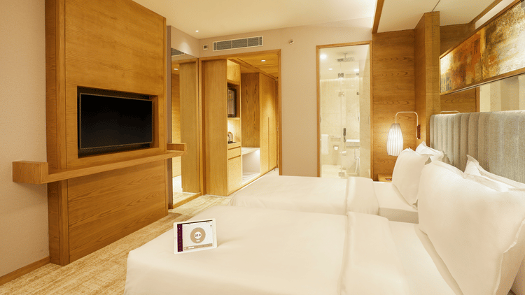 Side view of Premier Rooms featuring a wall-mounted TV and a bedside light in the corner at The Residency Towers Chennai