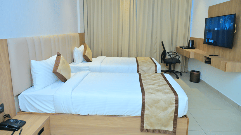 Bedroom of Bhavanis Vista By Icon featuring a bed, a headboard, a desk, and a television.