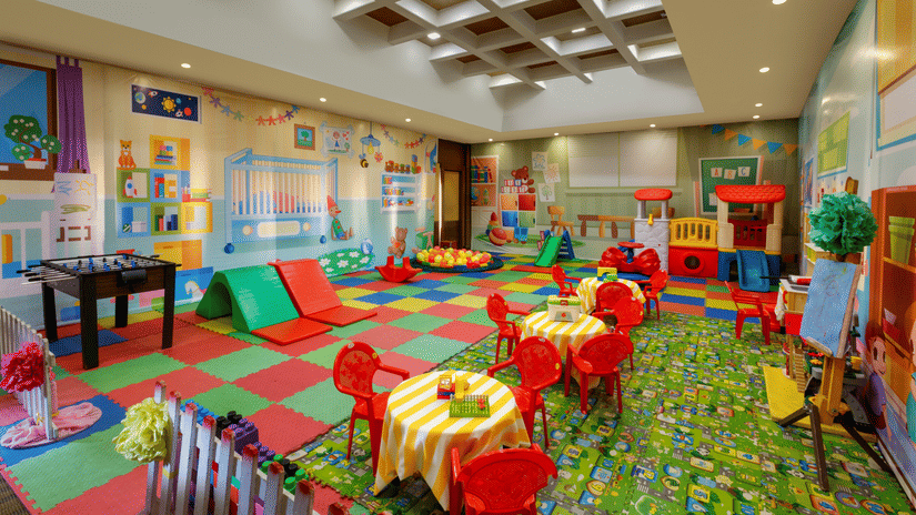 Children’s play area with small tables and chairs, colourful mats, toys, storage shelves, and ceiling lights at Heritage Village Resort & Spa, Manesar.