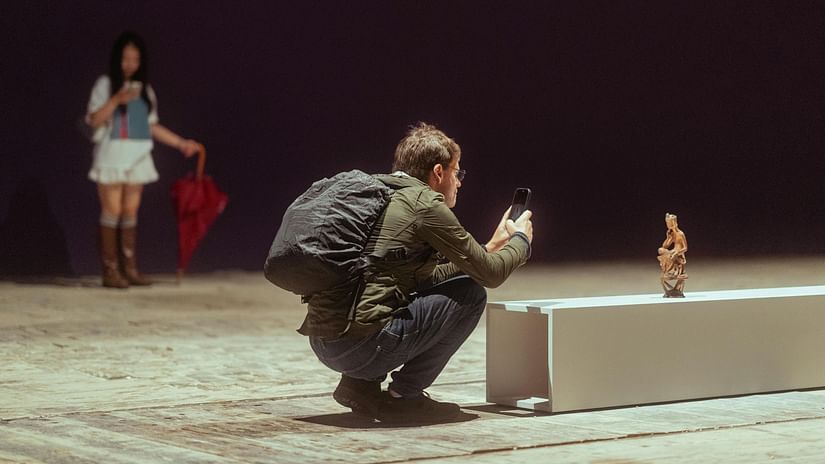A man taking a picture while a woman is at the background