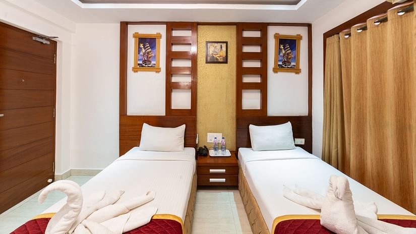 Room entrance view of the Deluxe Twin Room showcasing two single beds placed against a wooden feature wall, maintaining balance, symmetry, and simplicity.