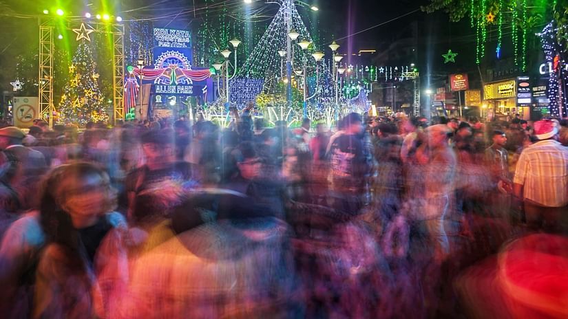 A bustling city street at night with colourful lights and blurred motion of people.