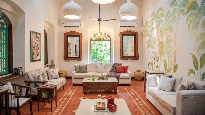 A living area with sofas and centre tables, photo frames on the wall, tables on each corners where decorative items are placed at Lamrin Ucassaim Hotel, Goa