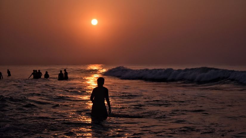 A man taking a dip in the ocean during sunrise