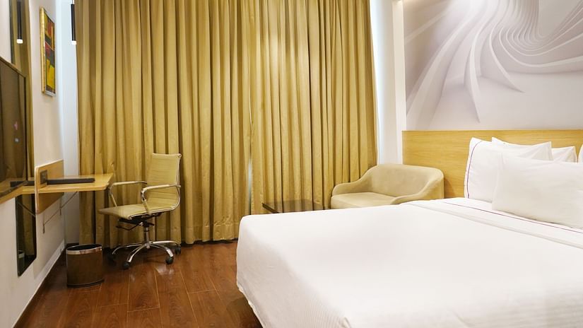 An image of a bedroom featuring a double size bed, flat TV screen, work and desk,  and other items - Nemsia