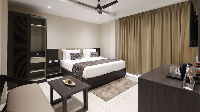 Premium Room at Pride Biznotel Canopus, Digha featuring a plush bed in front of a TV mounted on the wall and a sitting space with a couch and a coffee table
