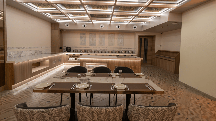 A brightly lit dining room with a buffet area, a seating area and a patterned ceiling with integrated linear lighting | Pride Elite Chhatrapati Sambhajinagar