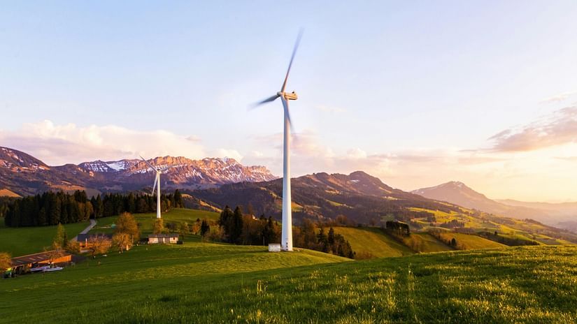 An image of a windmill farm with greenery around