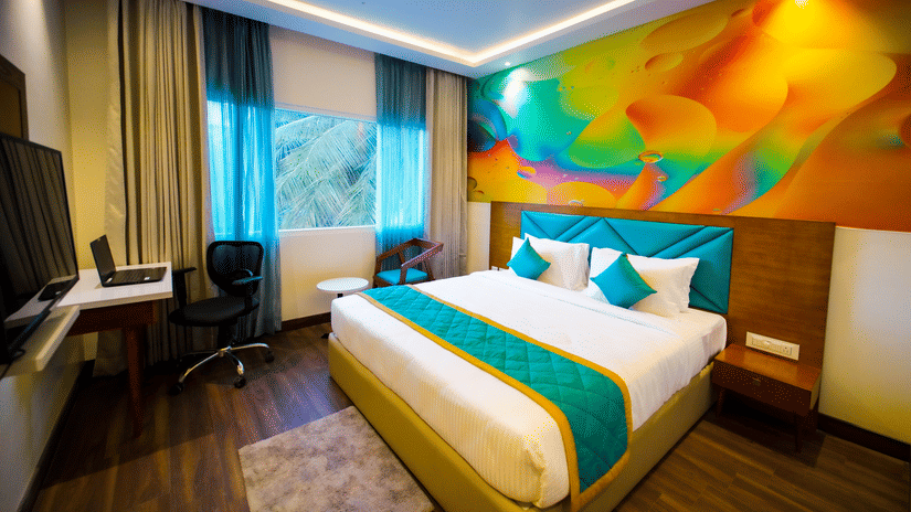 Modern superior room interior at Quality Inn Rockwell Grand, Bangalore featuring a comfortable bed, vibrant wall art, and stylish decor.