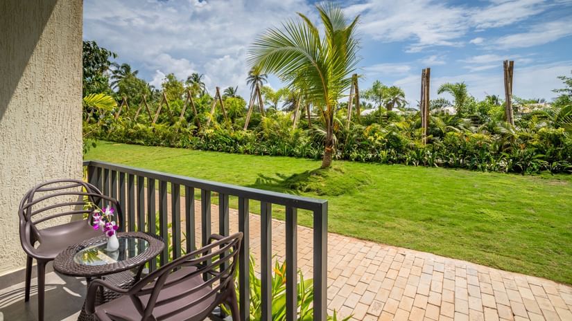 image of the balcony at the premium cottage opening to a lush green lawn on a sunny day with seating area on the porch
