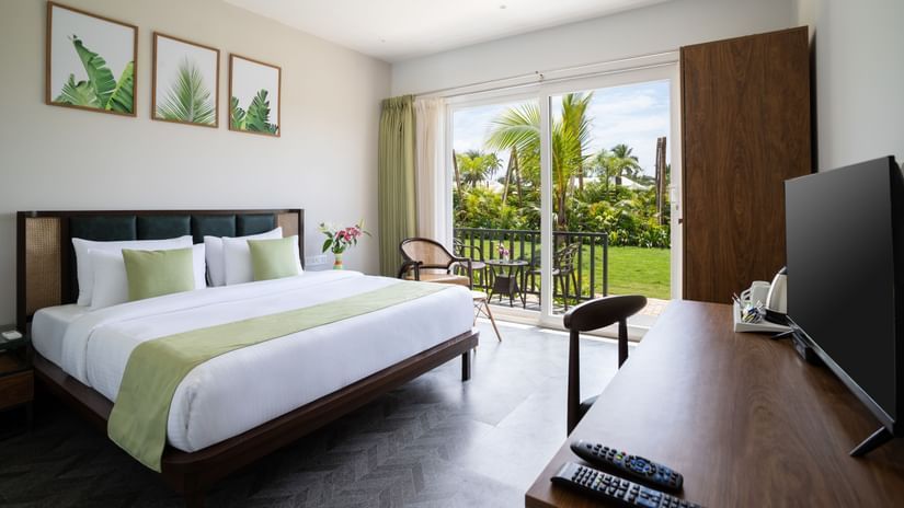 full view image of the premium cottage at sibaya beach resort in morjim beach, goa featuring a lush green scenic view from the huge windows in the room