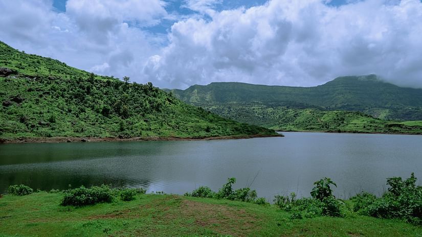 View of a lake with mountains and cloudy sky in the background.