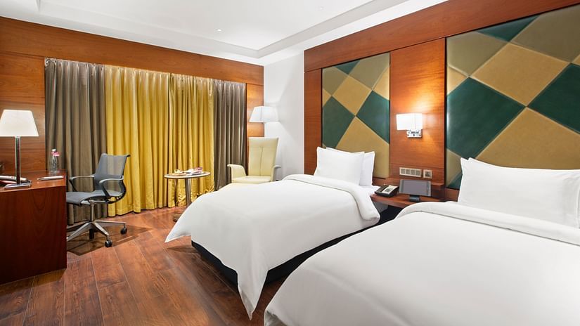 Executive Room with two cozy beds and a corner seating area at The Residency Towers Coimbatore
