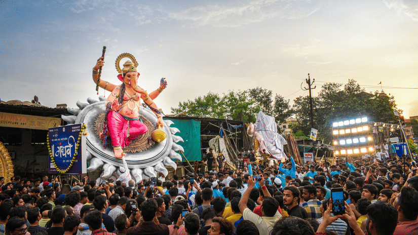 An overview of a Ganpati pandal in Mumbai with a procession of numerous people surrounding the idol.