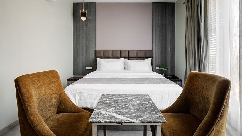 Grey themed Deluxe room room with chairs and a table - The White Moon