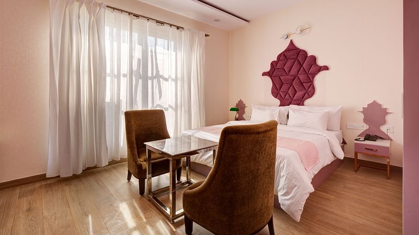 Pink themed Super Deluxe Room with king size bed, chairs and white curtains - The White Moon