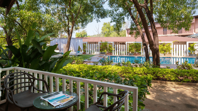 The patio and surrounding greenery of the pool front cottage room - White Woods Resort, Morjim