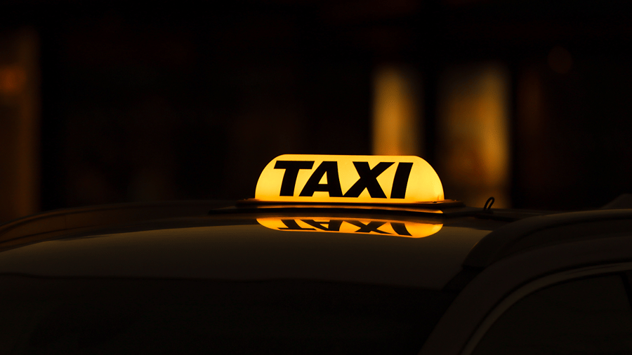 Illuminated yellow taxi roof light on a car at night for travel and cab pickup services.