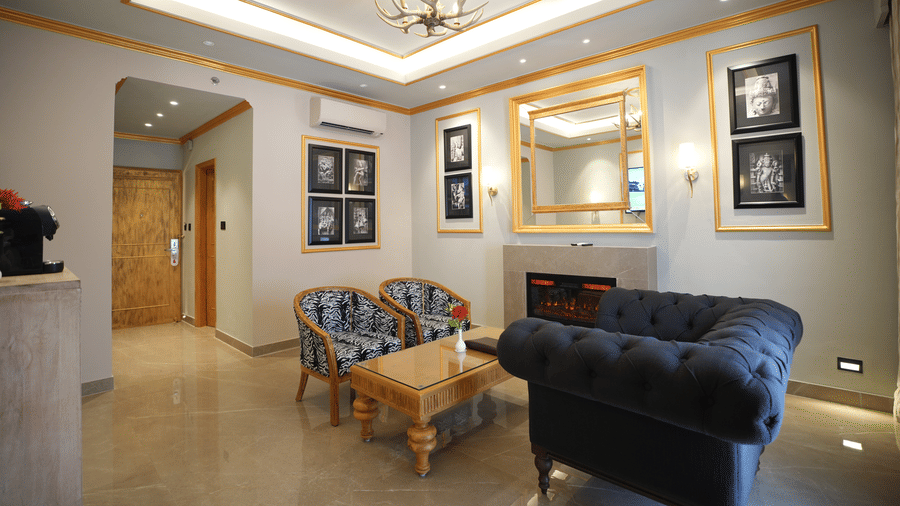 An Executive Suite living area at Clarks Khajuraho with cushioned seating, a center table, framed wall art, and a well-lit ceiling design.