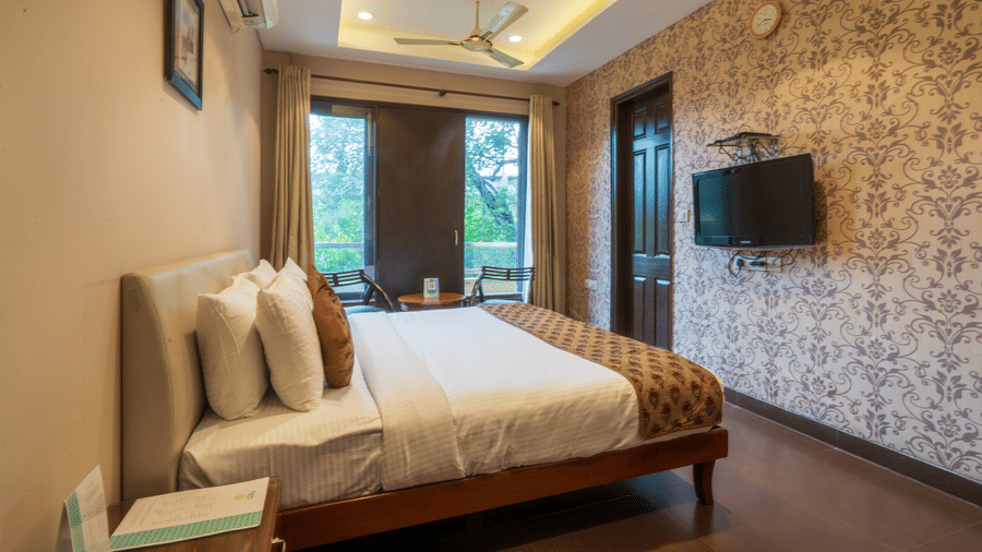 Room at Cosy Grand @Chanakyapuri by The Cosy Hotels with double bed, balcony view, and flat-screen TV.