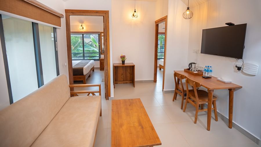 Sitting area with sofa, television, tabke and chair at Feel Free Retreat, Wayanad