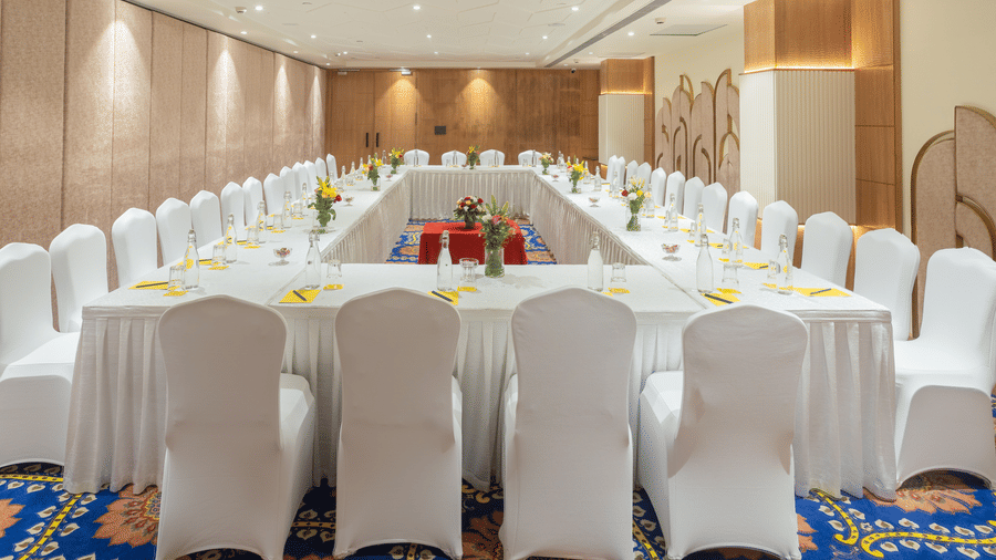 U-shape conference setup at Golden Tulip Jaipur City Center with white-covered chairs, table setup, floral decor, and water bottles, ideal for meetings and workshops.