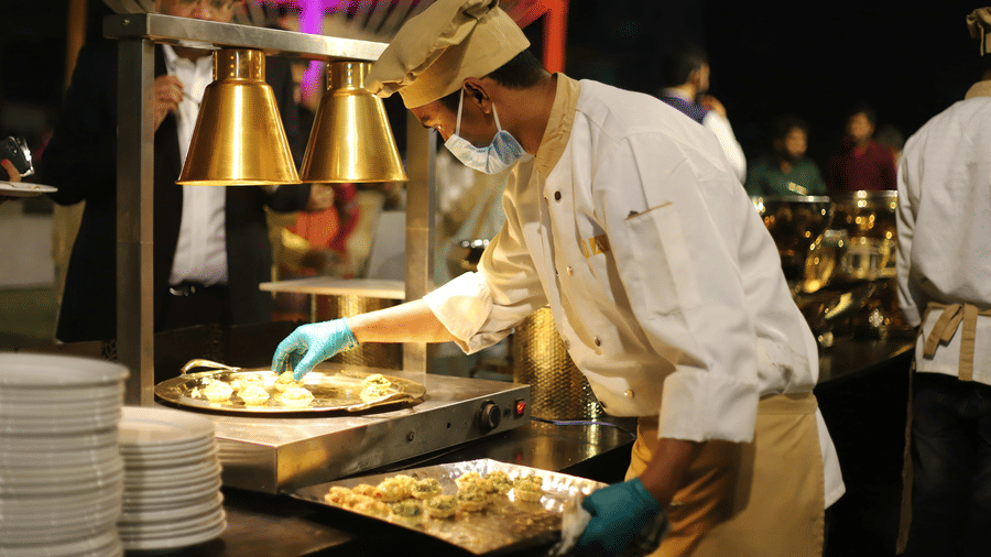 A chef preparing fresh appetisers at a live catering station during an outdoor event.