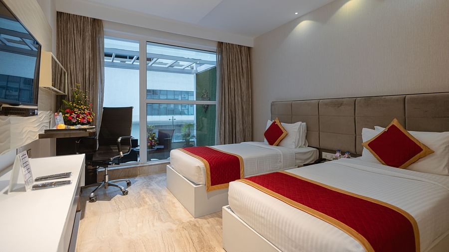 Side view of two cozy beds and a wall-mounted TV in a Club twin room at Icon Premier Hotel by Bhagini, Devarabisanahalli