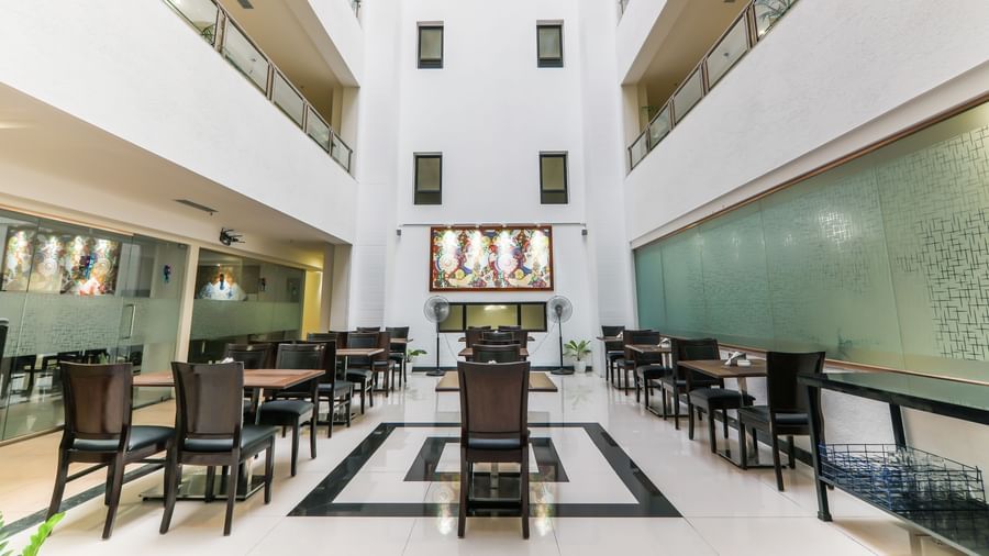 Dining area at Nexas Square, Viman Nagar featuring tables and chairs. It is a common area surrounded by buildings on all side.