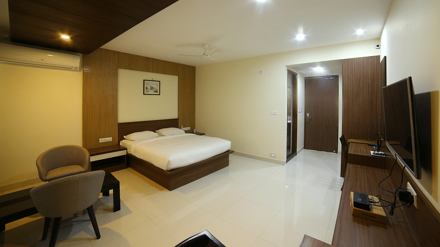 Mysore Gate Hotel, Bangalore Bengaluru A room featuring a well made bed sofa chairs a TV and a wall painting - Mysore Gate Hotel Bangalore