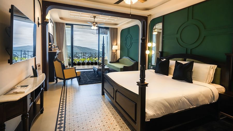 An image of a bedroom with king size bed, flat TV screen, chair, sofa, and a view of the balcony - Polo Orchid Resort, Cherrapunjee - Best Resorts Meghalaya