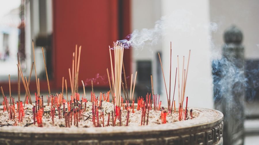 incense being burned in a bowl filled with sand inside a temple
