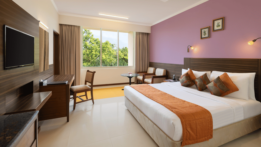 Double bed and a television inside the Family Room at Sangam Hotel for the ideal Rooms Near Thanjavur Railway Station