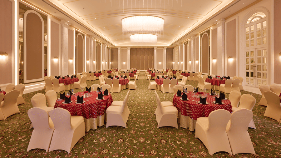 Banquet hall with round tables, chairs, and ceiling lights at Sarovar Premiere Amritsar.