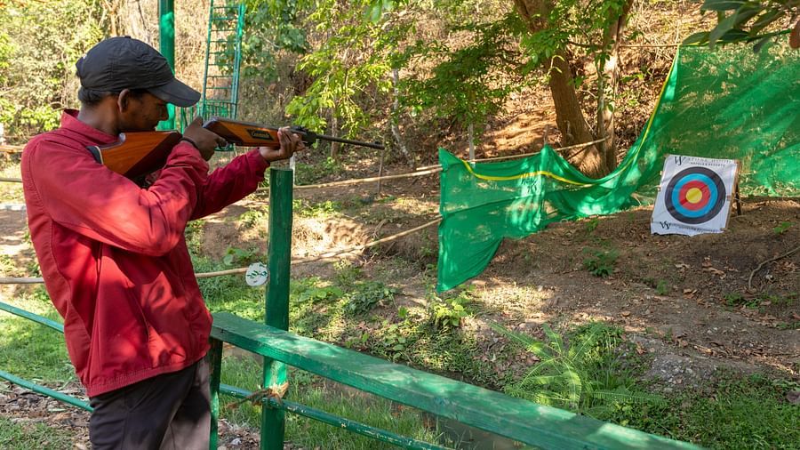 Man aiming at a target in an outdoor shooting range activity. | Stone Wood Jungle Resort, Dandeli