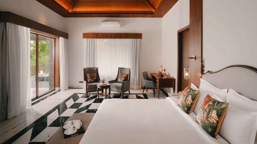 Bedroom at The Ananta Udaipur with a king bed and balcony overlooking the greenery.
