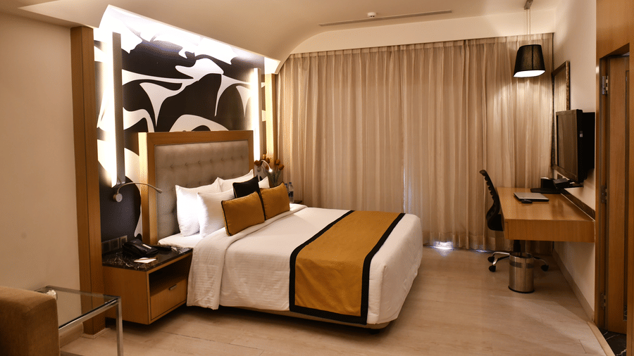 Hotel room with warm lighting, a cosy bed, desk area, and contemporary interior design.
