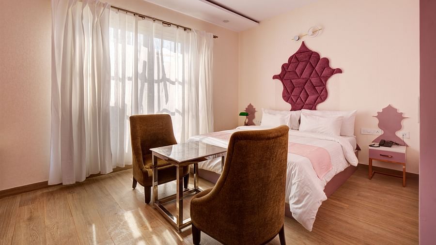 Pink themed Super Deluxe Room with king size bed, chairs and white curtains - The White Moon
