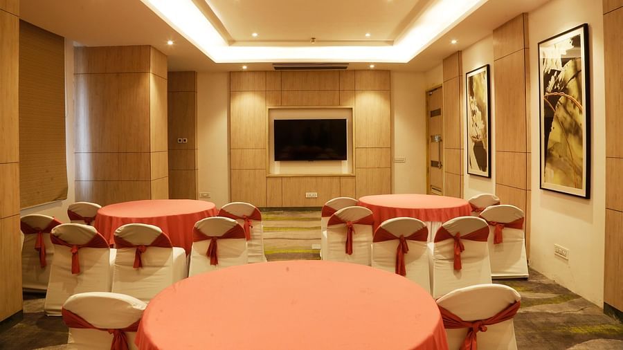 A conference hall in Zirakpur with the chairs turned towards a wall with a mounted television - Tulip Inn, Zirakpur